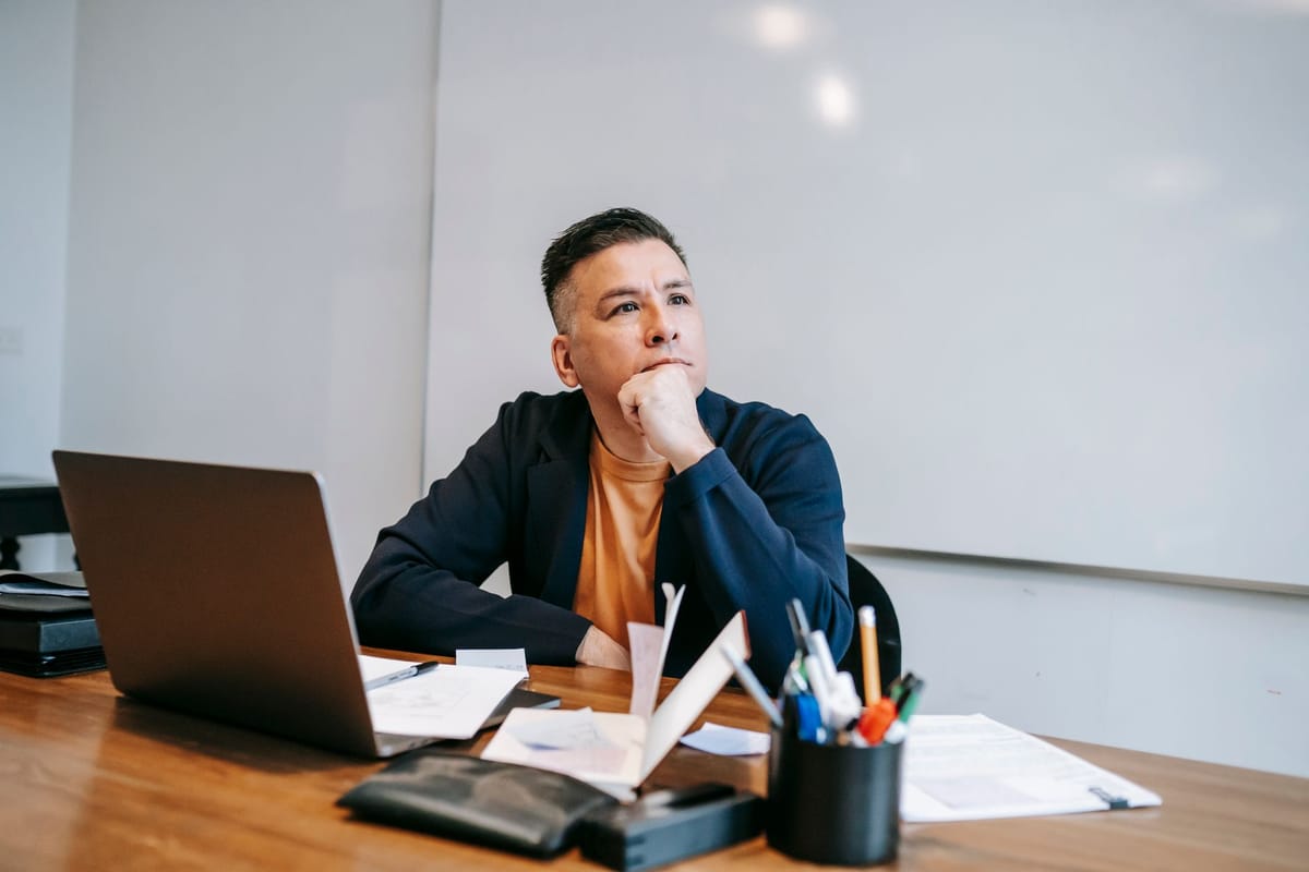 Un dirigeant réfléchit à son bureau, entre ordinateur et paperasse, face au numérique