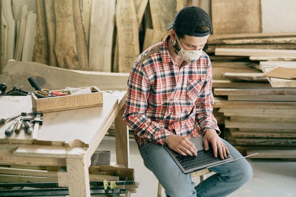 L'artisan est dans son atelier et occupé à saisir des données sur son ordinateur